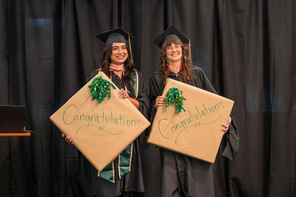 On stage at MPH graduation, standing next to my classmate Carina. We’re both smiling and holding awards after being selected as Faculty Picks for our thesis poster presentations.