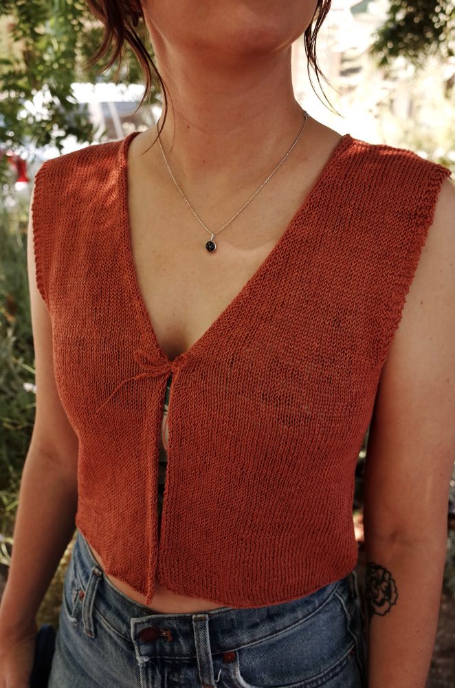 Stockinette vest with open front, deep v neck line, and 1x1 rib edging around the arm openings. Knit from burnt orange linen yarn at a loose gauge. 
