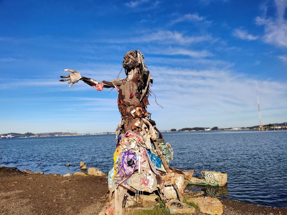 Sculpture, made of wood and found objects, standing on Albany Bulb, East Bay, with outstretched arms.