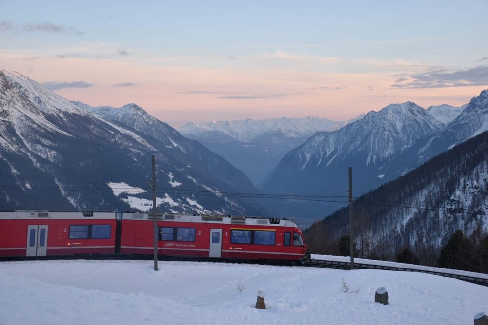 The view over Val Poschiavo with a Rhätische Bahn train heading down in the foreground