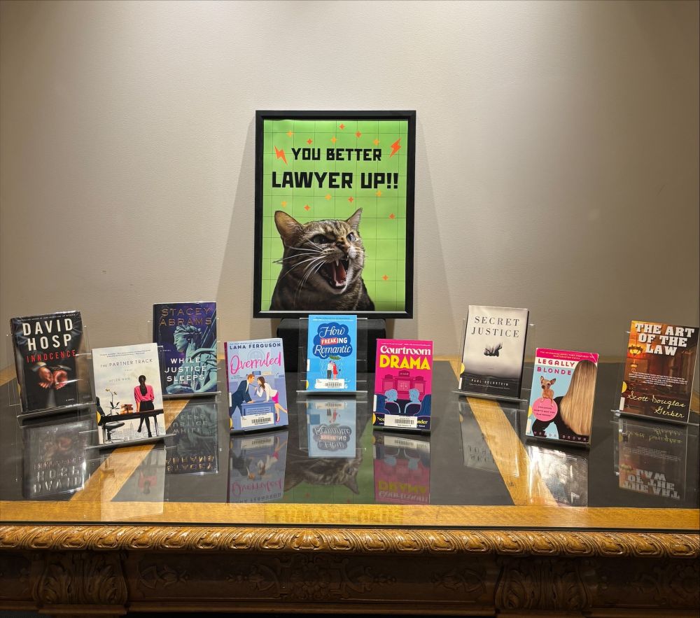A display of nine books on a table. Signage reads, “you better lawyer up!”