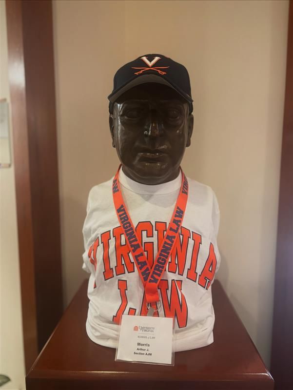 A bust of Arthur J. Morris wearing a UVA ball cap, Virginia Law t-shirt, and UVA Law lanyard.
