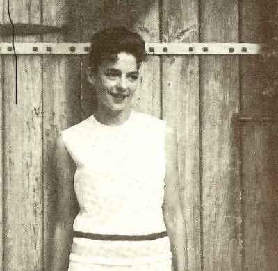 Rosel in a white sleeveless shirt against a wooden barn door