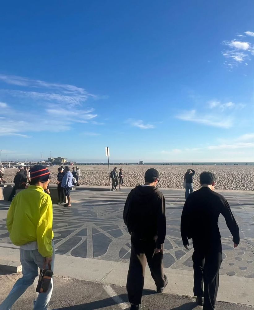 Namjoon and Jimin, both dressed in black from head to toe, walking toward the beach (part 1 of 3).