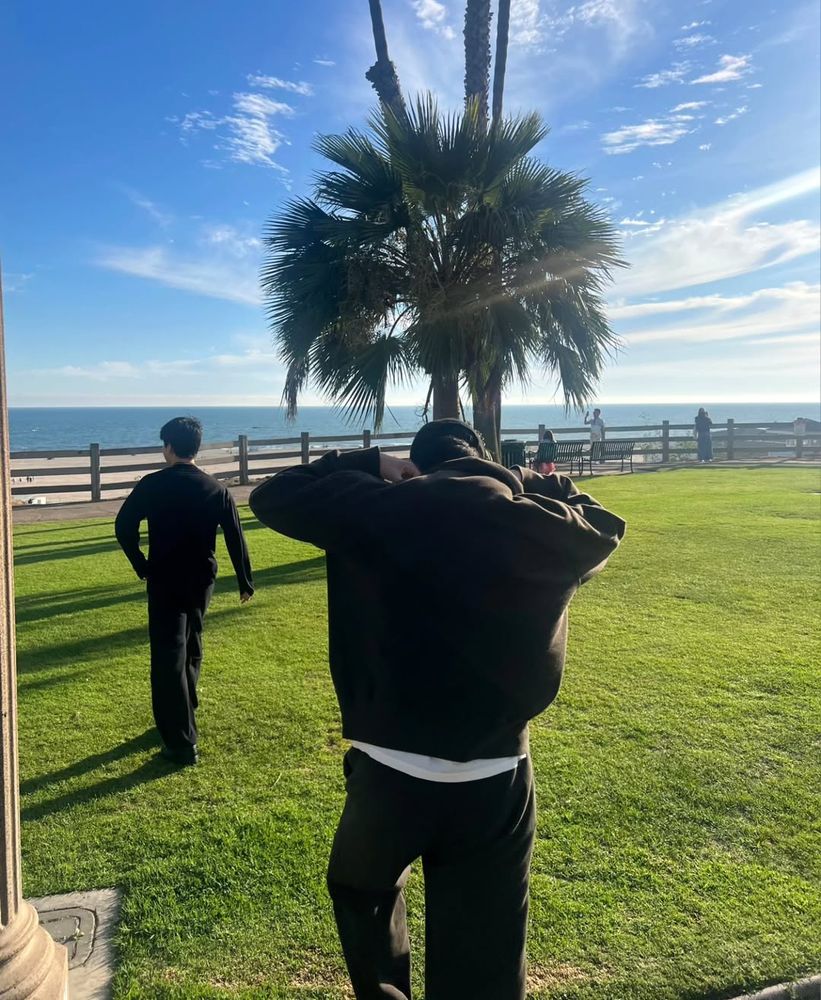 Namjoon and Jimin, both dressed in black from head to toe, walking toward the beach (part 3 of 3).