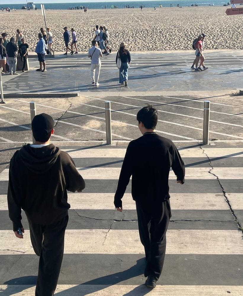 Namjoon and Jimin, both dressed in black from head to toe, walking toward the beach (part 2 of 3).