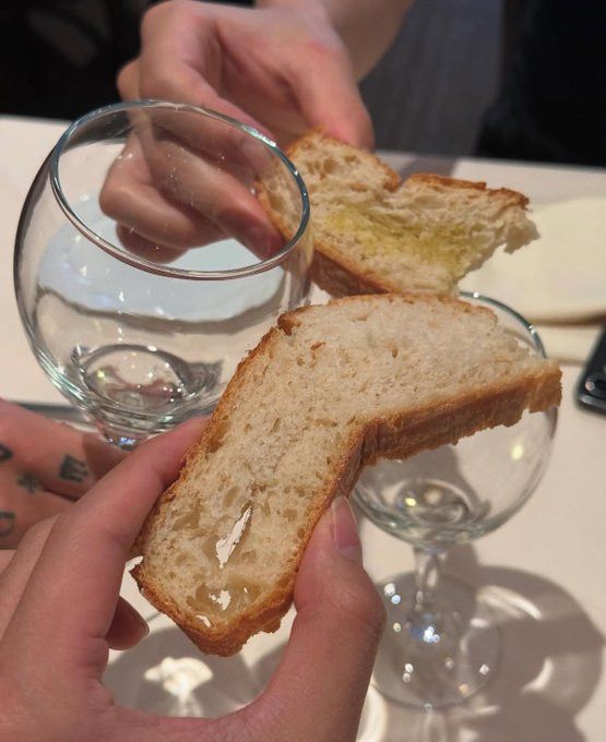 A photo of Taehyung, Jimin, and Jungkook's hands. They are toasting. Taehyung and Jimin are toasting with slices of bread. Jungkook is toasting with an empty glass.