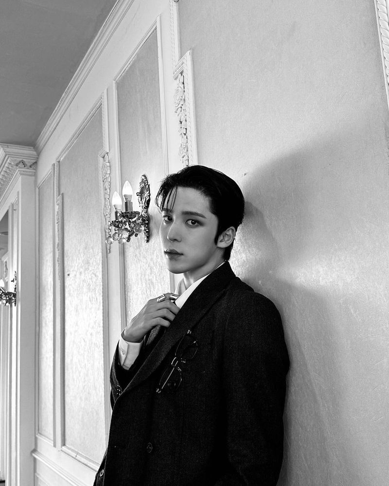a black and white photo of jeong yunho being the most seductive person known to humankind. he is giving the camera serious bedroom eyes and tugging at the collar of his dress shirt like he's about to rip it (and my heart) open further.