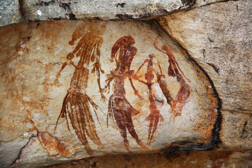 Picture of the Gwion Gwion rock paintings, found in Western Australia, thought to be 12,000 years old. They depict stylised figures (dark on a pale rock), wearing ornate costumes. 