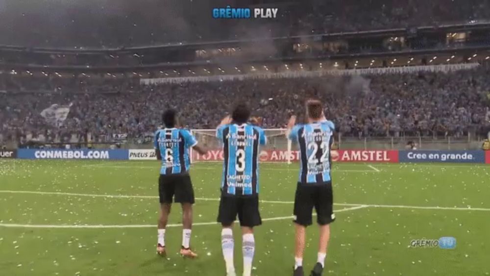 three soccer players standing on a field in front of a banner that says ' amstel '