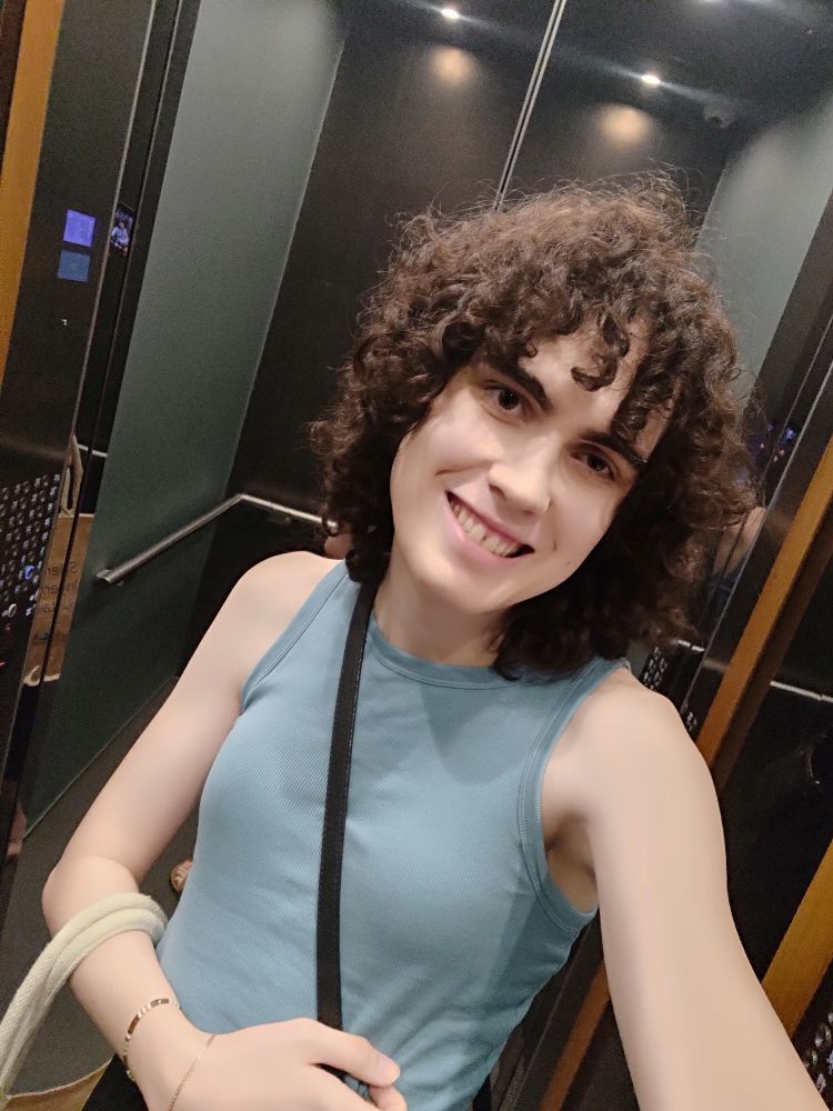 A selfie of me in a lift wearing a sleeveless top and carrying a leather crossbody bag.