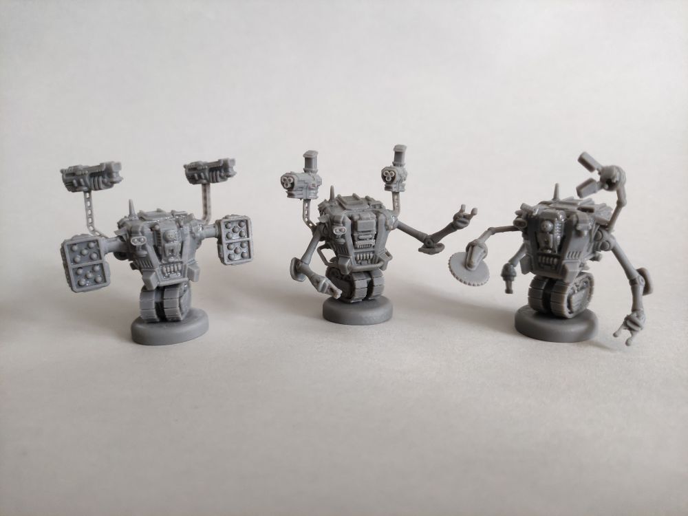 Wargames miniatures - three tracked robots with four arms each, front view.