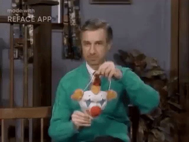 a man in a green sweater is holding a toy clown .