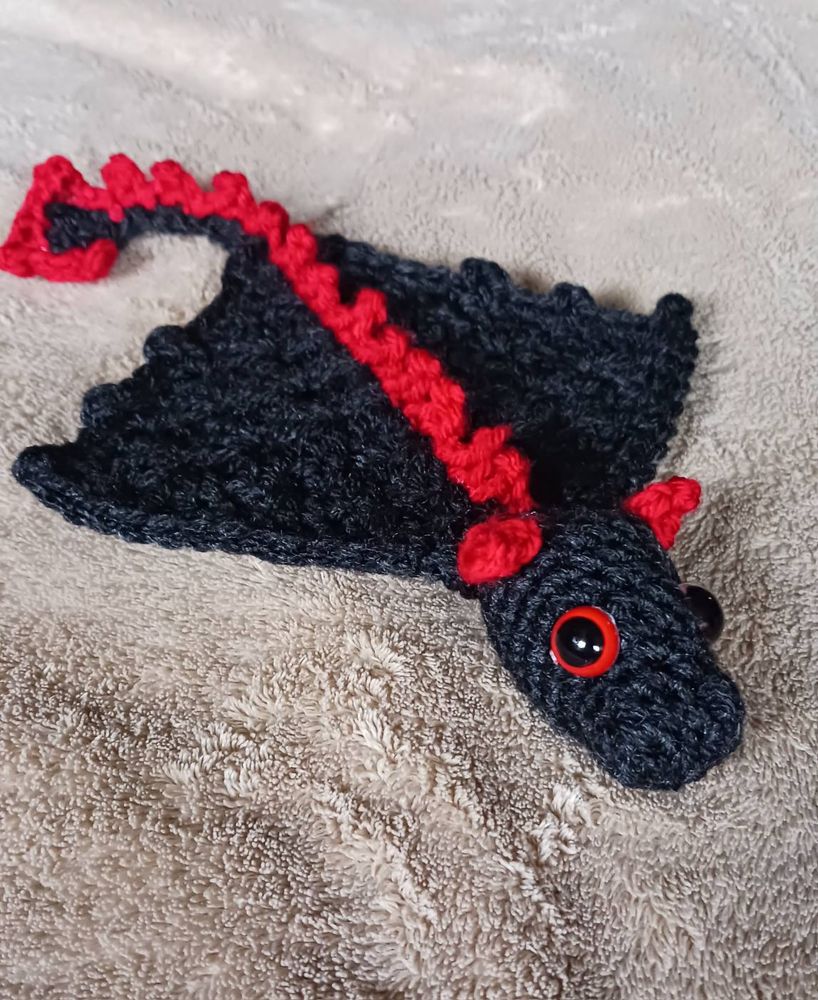 A black crocheted dragon with red horns, eyes, and spikes. 