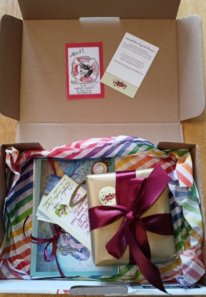Foto eines geöffneten Päckchens mit wunderschönen Karten und einer in Geschenkpapier eingepackten kleinen Box.