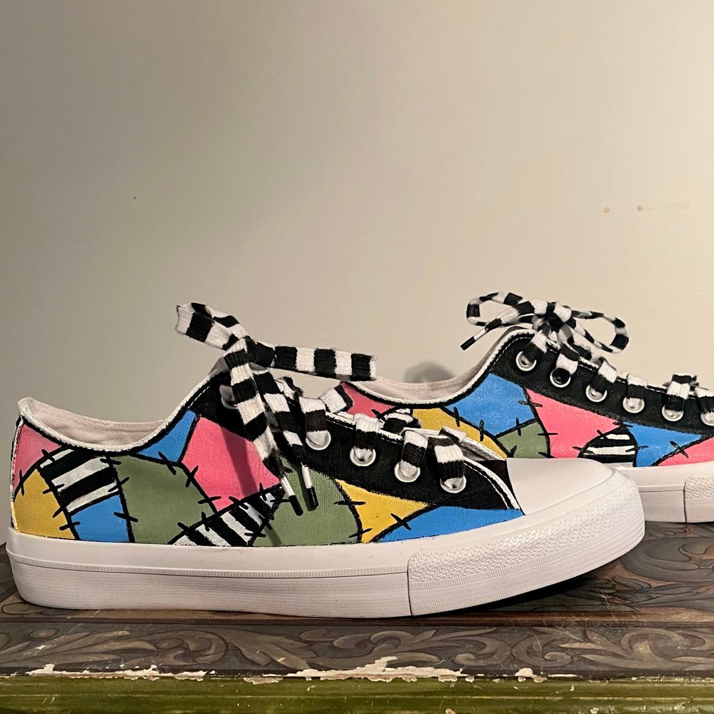 Handpainted sneakers using pastel pink, pastel green, light blue and bright yellow, with accents of black and white pinstripes and black stitches