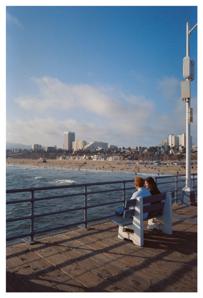 A couple sitting on a bench and talking at the Santa Monica Pier.