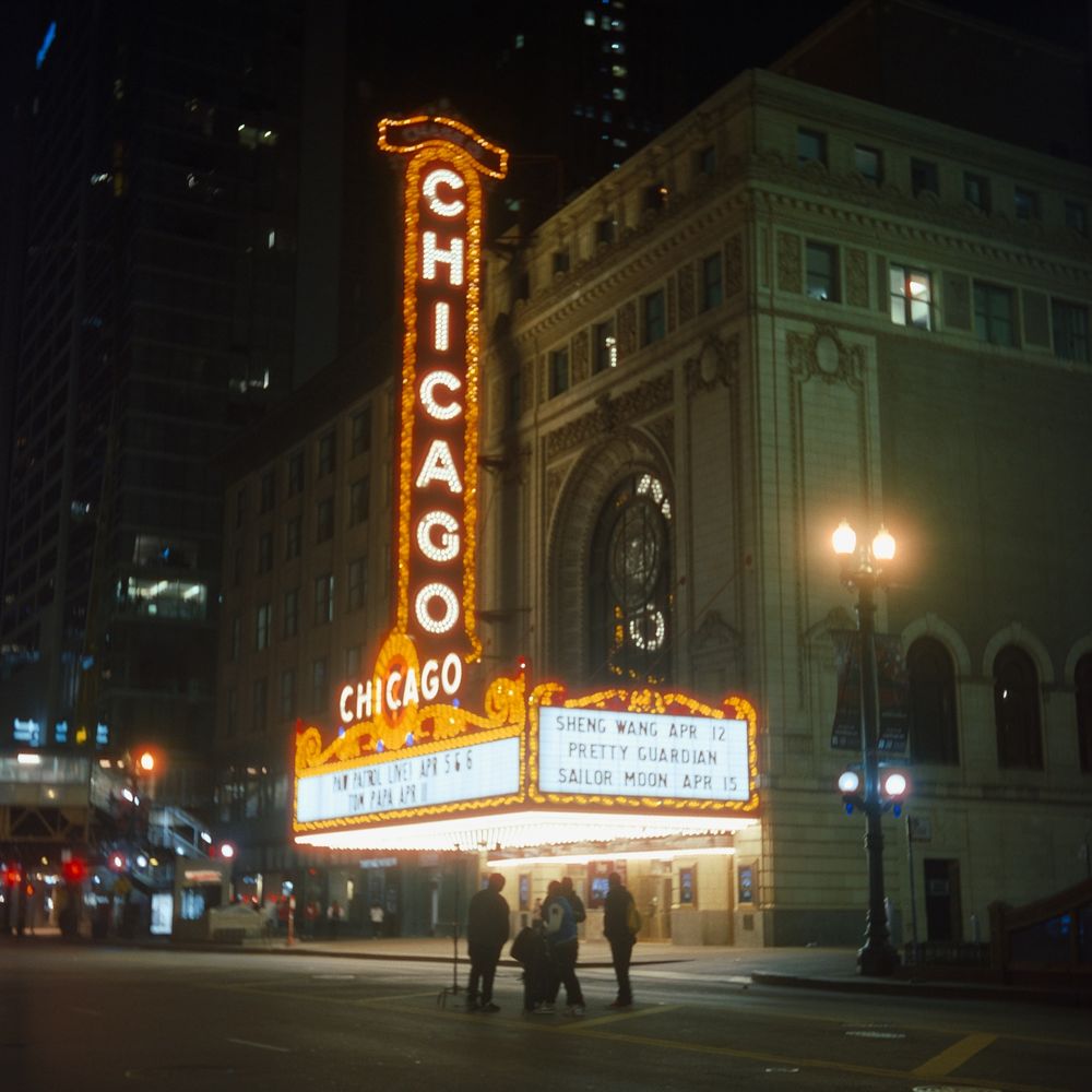 A couple men in silhouette preparing to shoot a music video in front of the Chicago Theater’s marquee. 