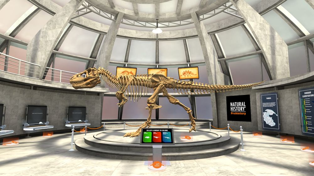 A large T-Rex skeleton standing in the central exhibit area of a circular museum hall with glass paneled roof, interactive fossil displays can be seen along the left wall and infographic panels can be seen along the right wall.  