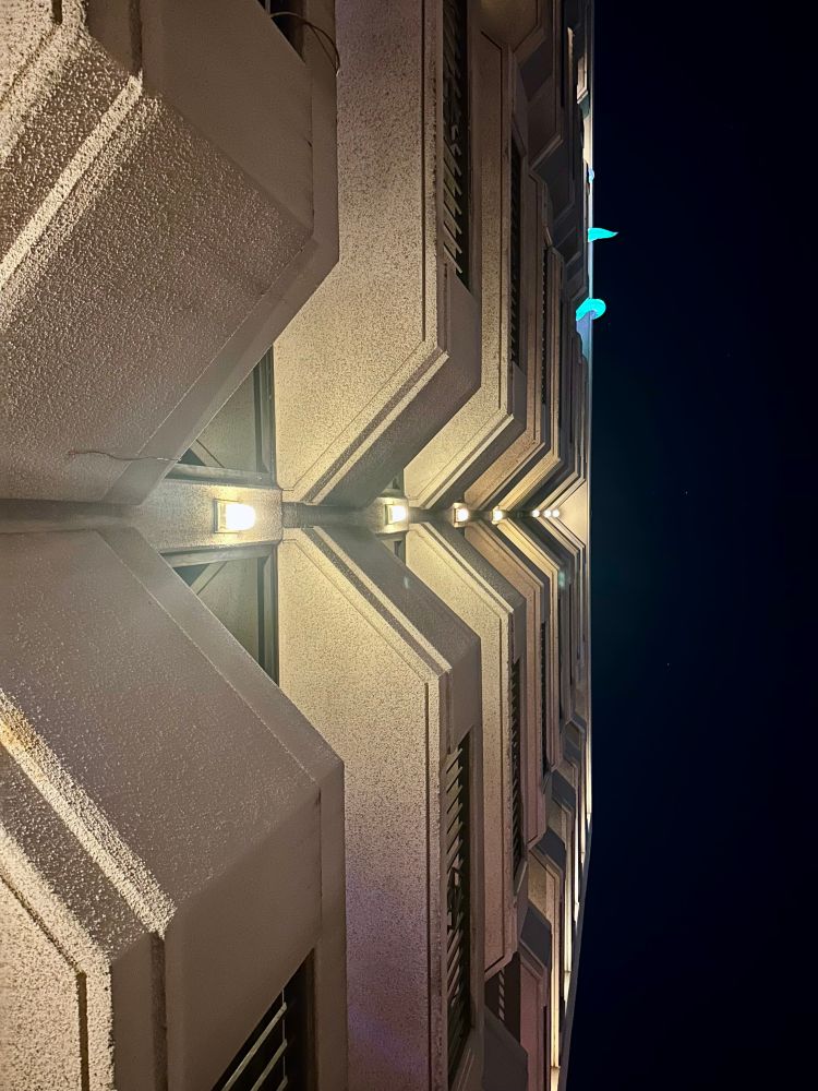 Night. Perspective shot looking upward at the balconies outside of a hotel. 