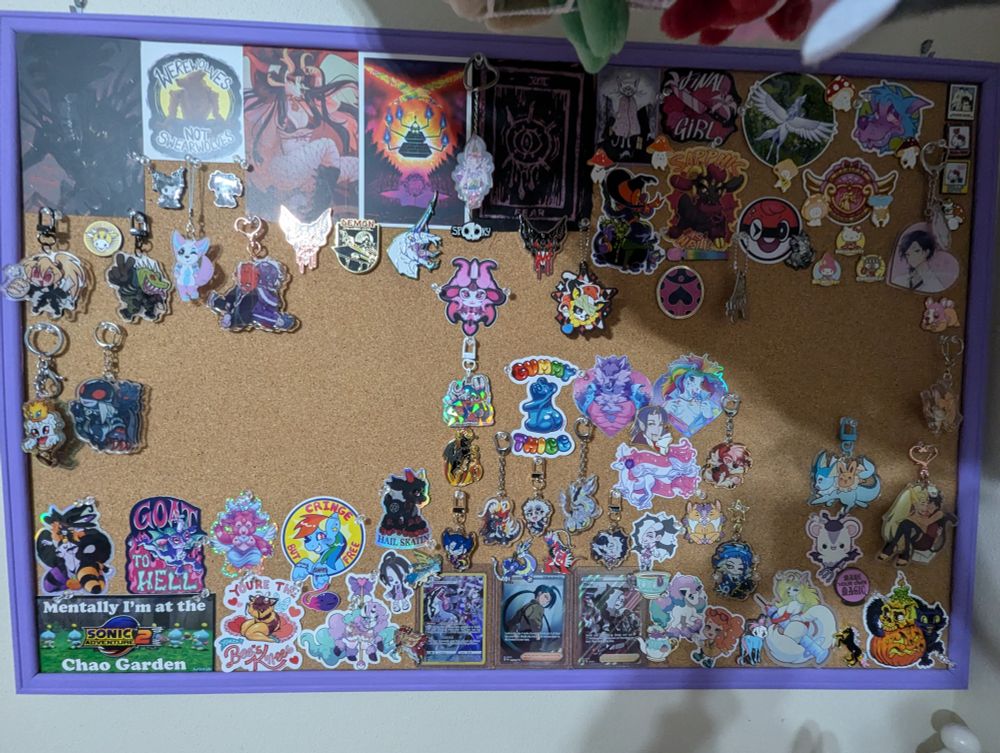 Pin board with small prints, stickers, enamel pins, and acrylic charms. Most themed off of furry, anime, horror, and Pokemon.