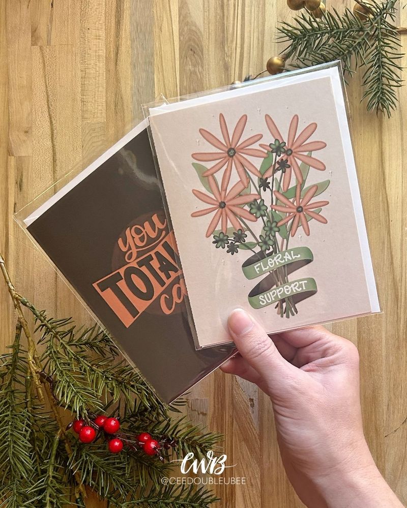 Hand holding a set of greeting cards "Floral Support" and "You Totally Can"
