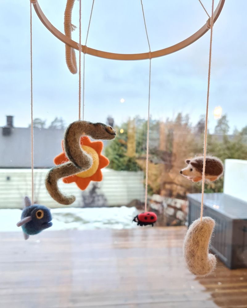 Uro med små figurer i ull, fisk, slange, sol, måne, marihøne og pinnsvin