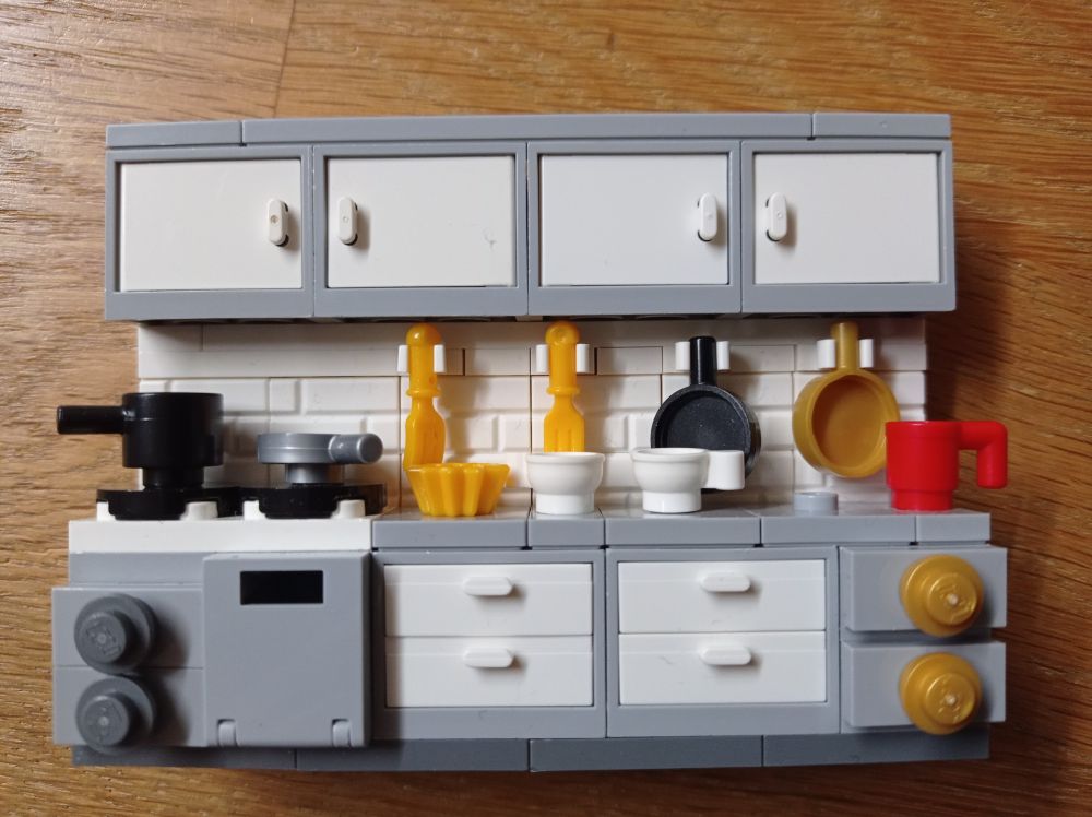 You see a grey-white lego-built kitchen in Lego-Minifigure-Scale
