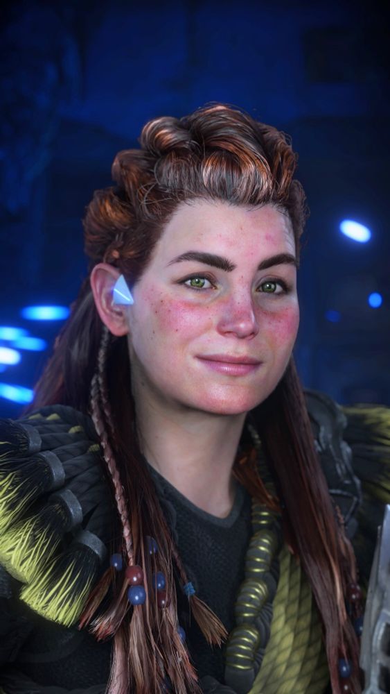 Aloy from Horizon Forbidden West smiling, with a blue background with blue sparks.