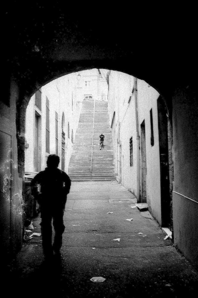 A photo of an urban site, we look ot of a tunnel and um a public staircase.
Black and white. 