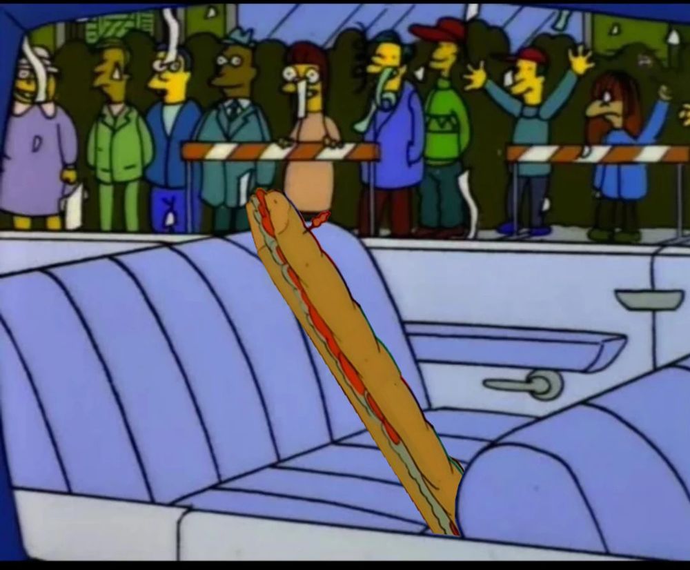Still from The Simpsons which shows a very long submarine sandwich in a car for a parade while people celebrate.