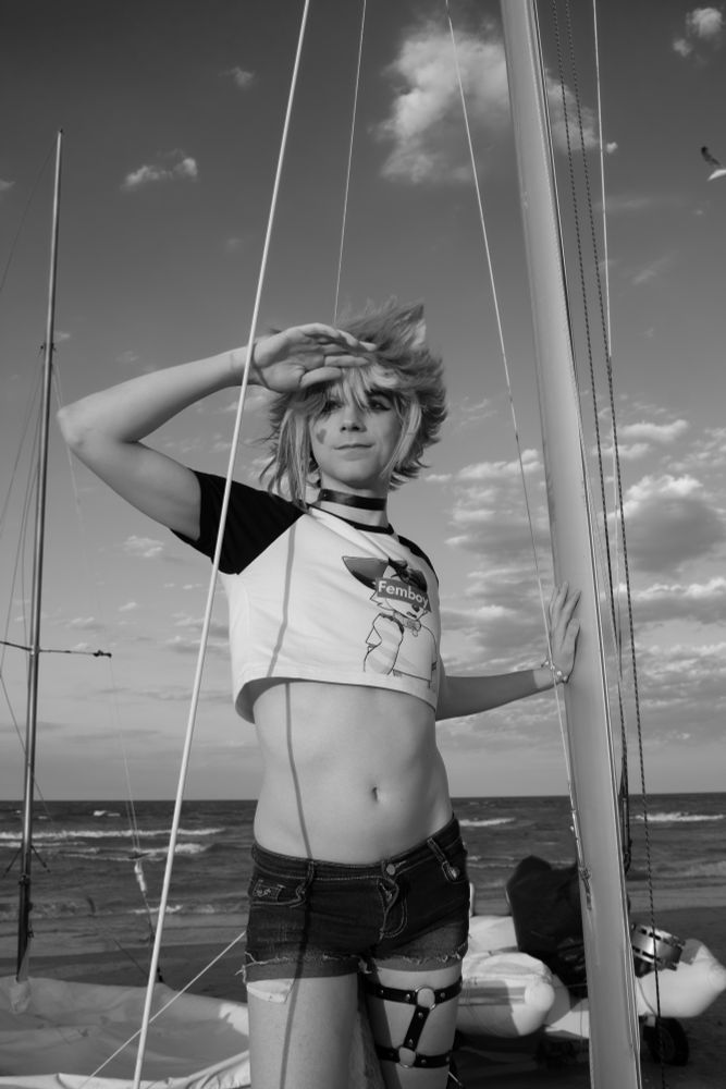 Picture of me cosplaying as Gorou from Genshin impact in a femboy casual version. I have my tummy and waist exposed by my cute small crop top and shorts revealing my thighs. 

In the picture I'm leaning against a pole from a small boat, and I'm looking away from the camera while protecting my eyes from the sun.

The picture is fully colored 
