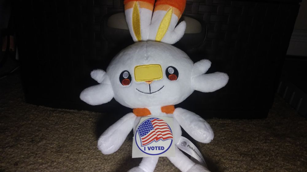 Scorbunny plushie with a sticker portraying an American flag above the text "I VOTED"