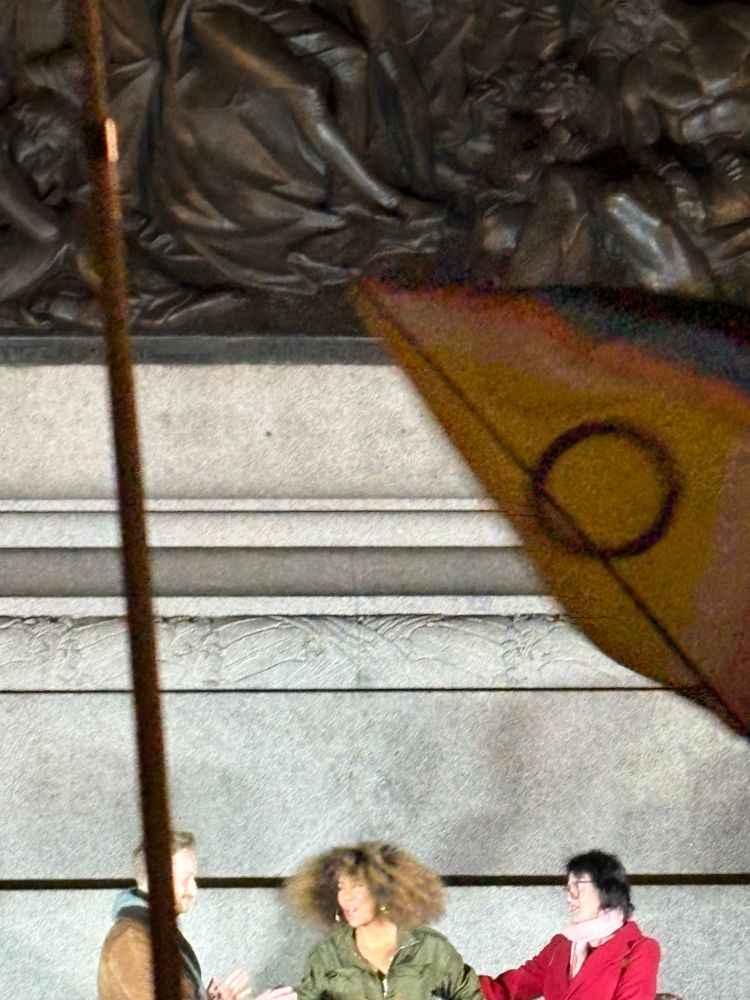 Olivia from trans legal clinic and former judge Victoria Macloud with an inclusive pride flag under Nelson’s column while speaking at TDoR 
