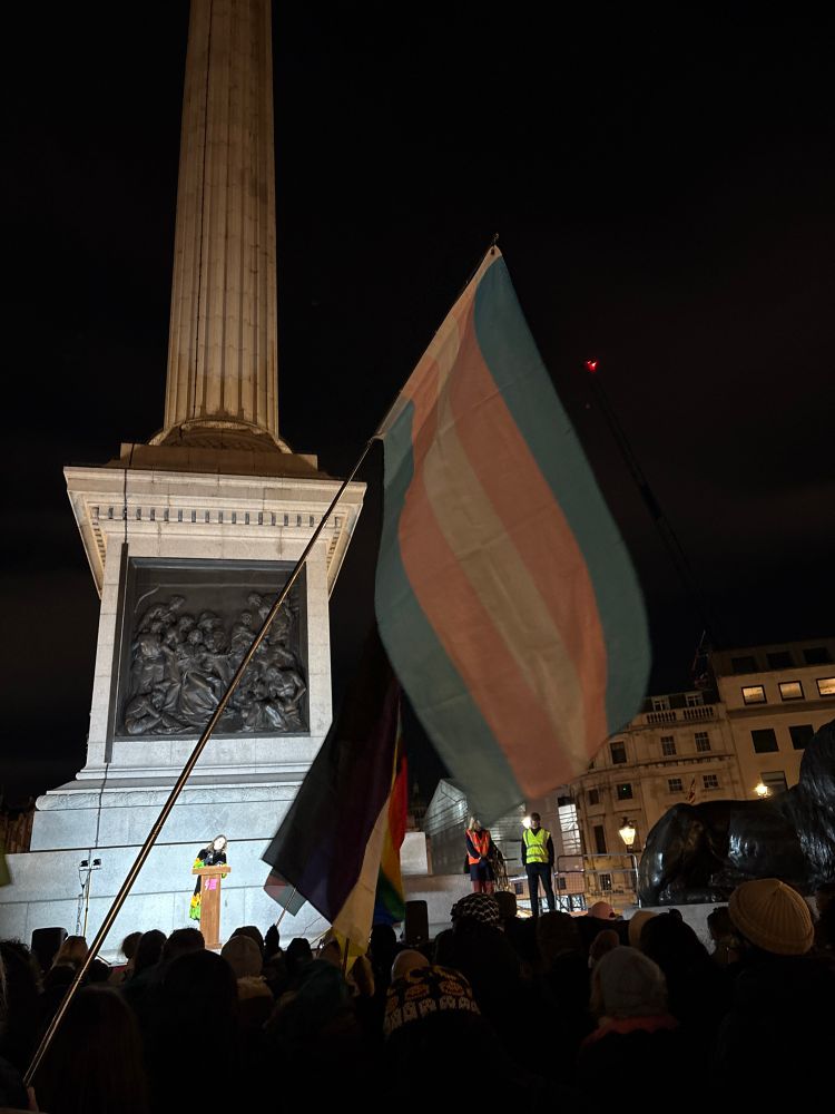 Kate Nash singer speaking. Surrounded by trans flags floating in the wind. 
 
