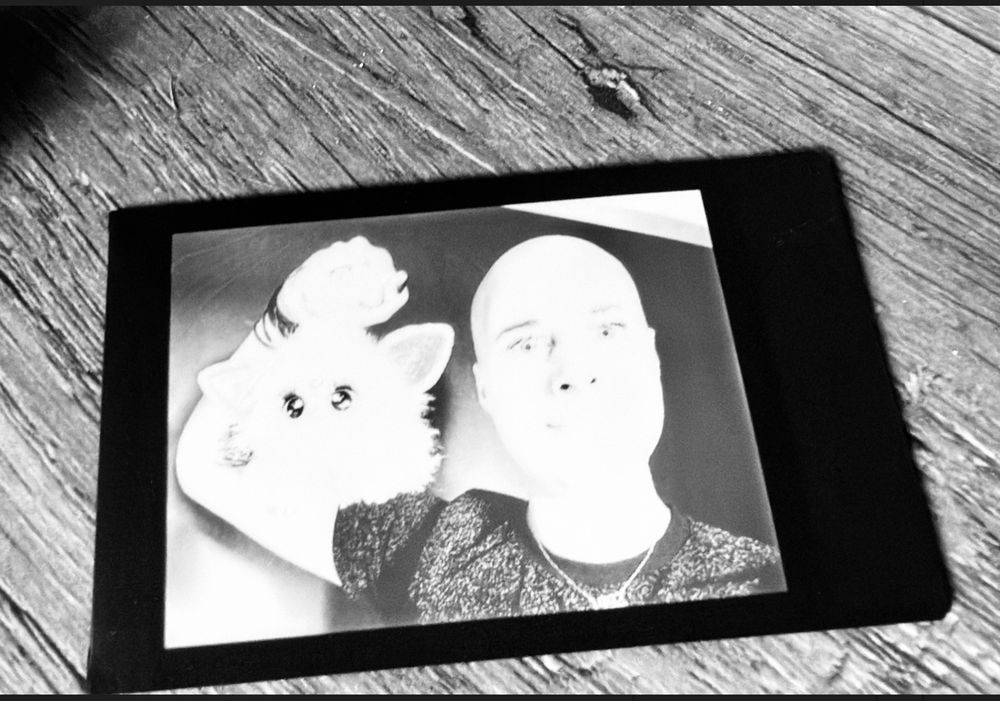 Black and white photo of polaroid of Caelan Conrad holding up a furby 