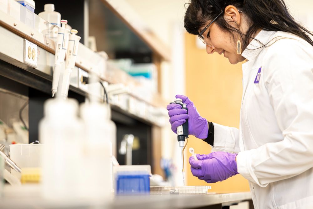 Mollie Ball in the lab holding a syringe while doing DNA research.