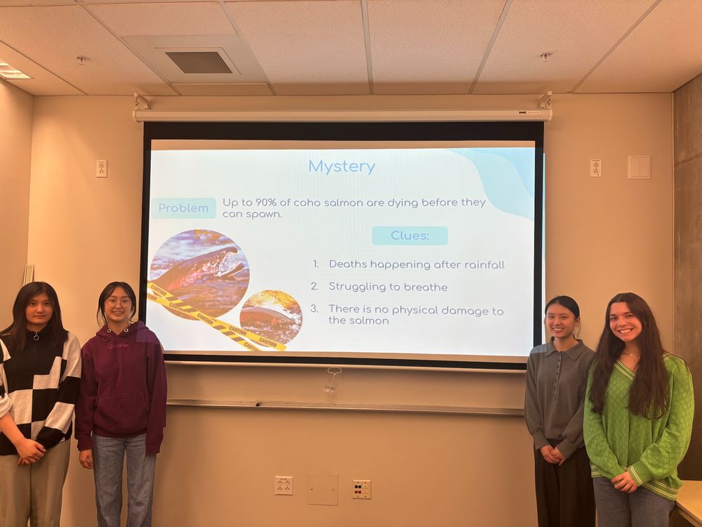 Three high school students and SAFS grad student stand in front of a presentation screen