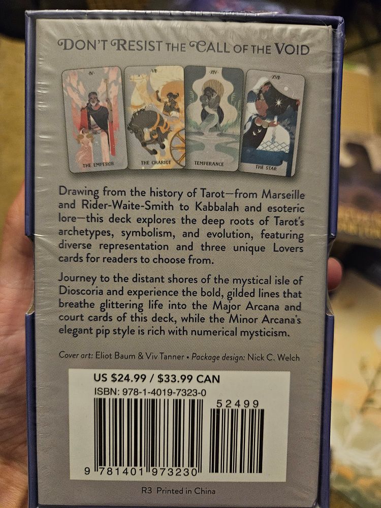 The back of the deck box. It says "Don't resist the Call of the void" boldly on top with some art of the cards within. The synopsis says "drawing from the history of tarot, from marseille and rider-waite-smith to kabbalah and esoteric lore- this deck explores the deep roots of tarot archetypes, symbolism and evolution... journey to distant shores of the mystical isle of dioscoria and experience the bold, gilded lines that breathe glittering life into the major arcana and court cards, while the minor arcana elegant pip style is rich with numerical mysticism."