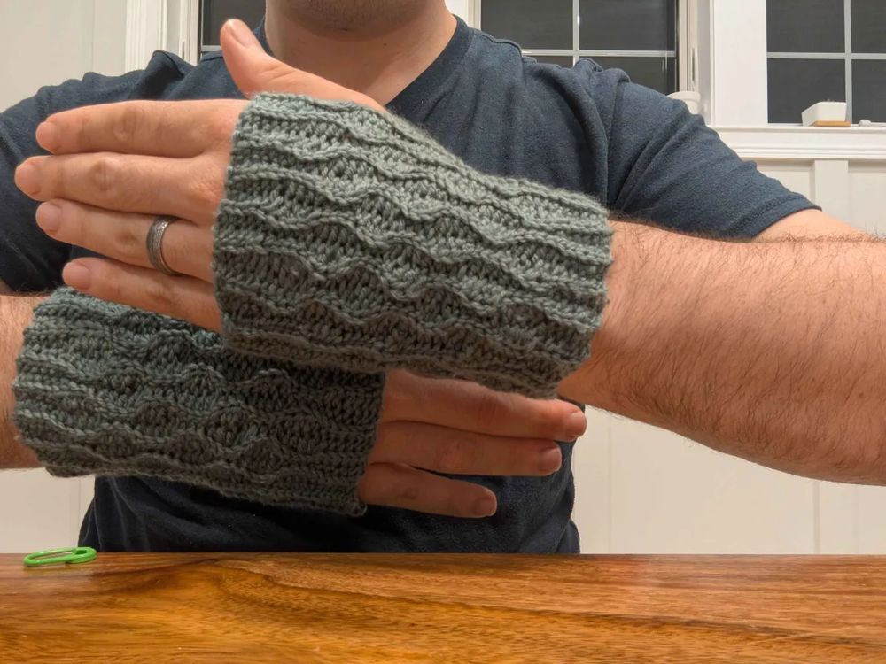 Crocheted fingerless gloves with a waving cable pattern.