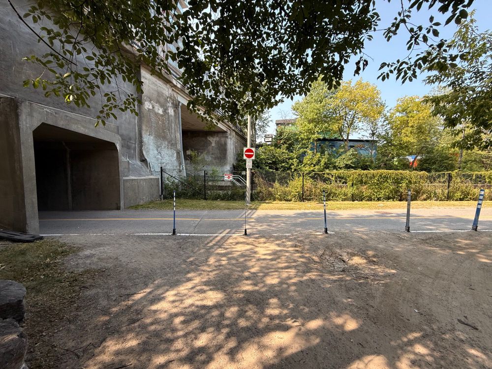 An intersection between a section of gravel road and a multi-use pathway leading into a tunnel