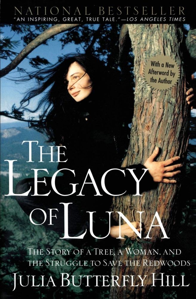 Book cover - Image background: young white woman with long dark hair. She’s wearing black, in a redwood tree, embracing the trunk. Vista of mountains behind her. Text reads: The Legacy of Luna, the story of a woman, a tree, and the struggle to save the redwoods. Julia Butterfly Hill