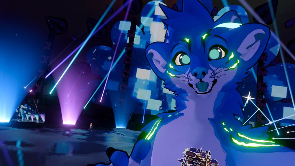 A four eared blue Fennix (me) looking into the camera with a happy smile. behind him is the stage with fish!‘s set
