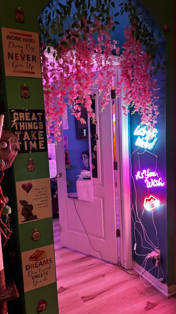 Doorway with pink flowers overhanging. Signs adorn the sides with words.