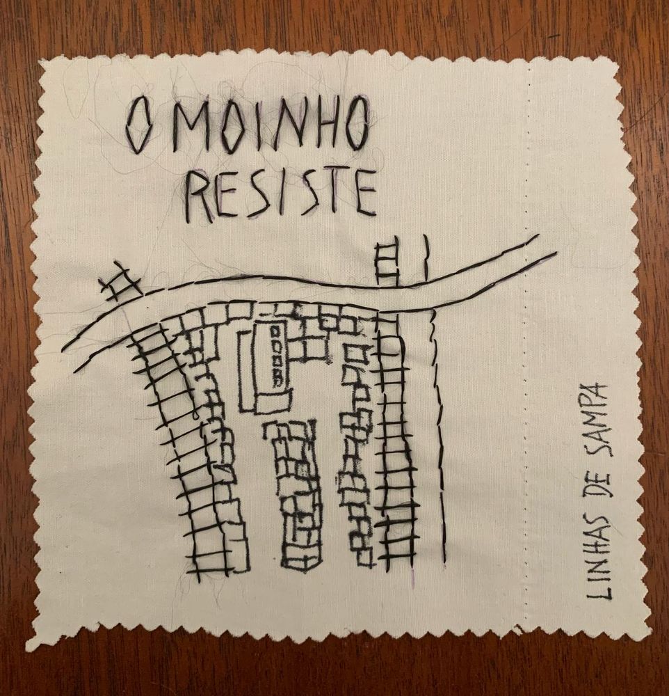 quadrado de algodão cru com um "mapa" da favela do Moinho às margens do Tietê bordado em fio preto. Acima, bordado em letras maiúsculas e fio preto "O MOINHO RESISTE". assinado Linhas de Sampa 