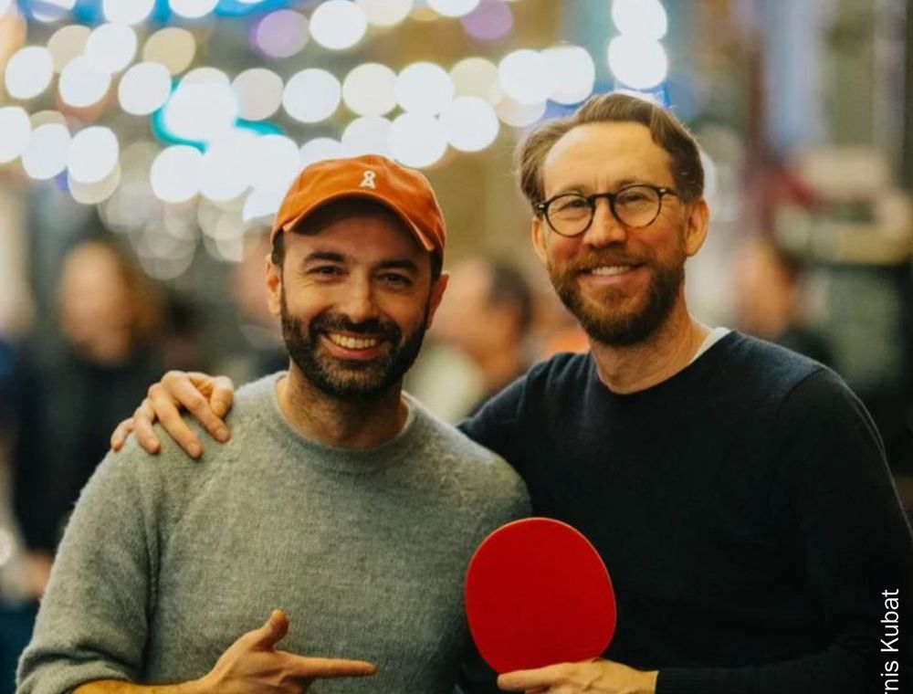 Unangenehme start up Dudes lächeln und halten einen Tischtennis Schlägel