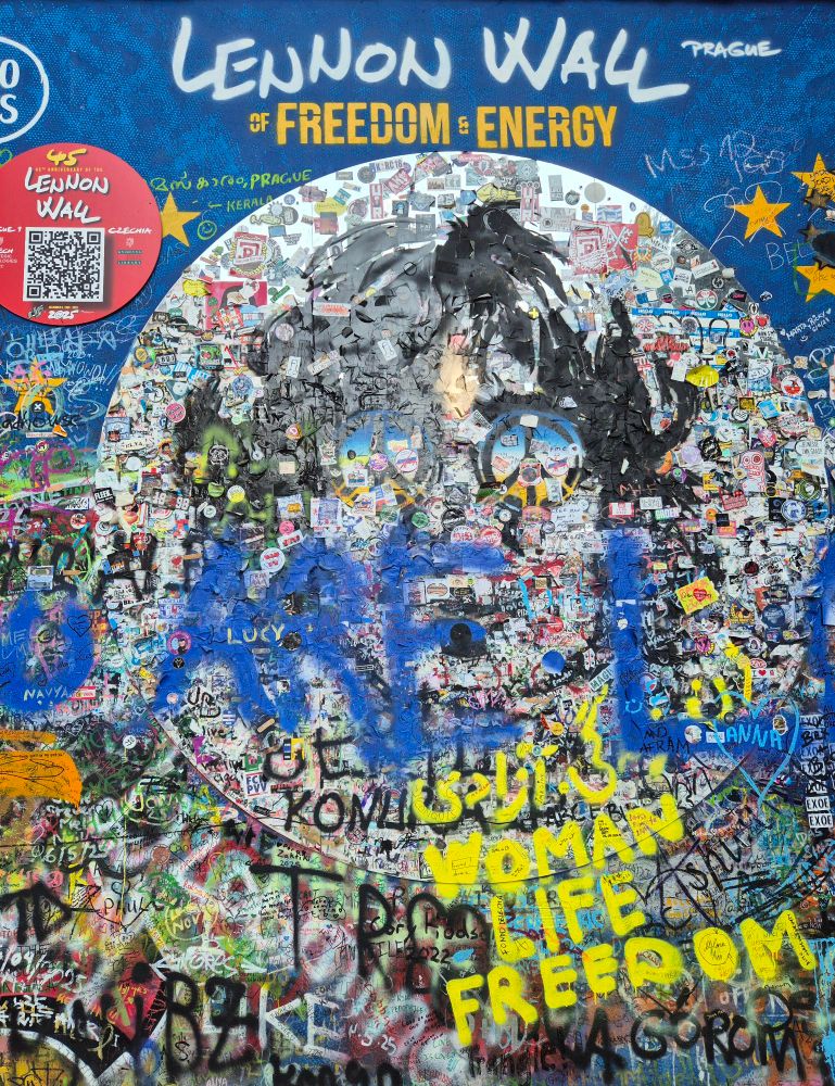 Wall covered in graffiti. At top reads Lennon Wall, freedom and energy. 