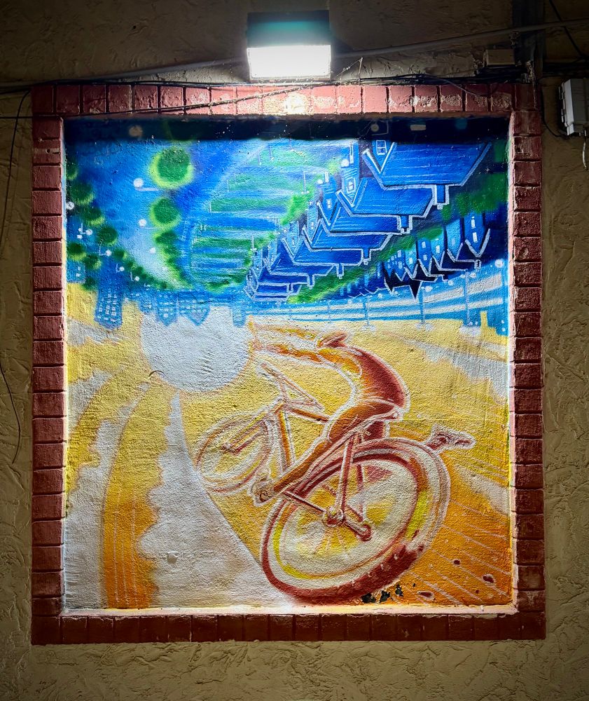Photo of a surrealist painting of a person a bike riding a ray of sunshine above and upside down from a row of houses in a city