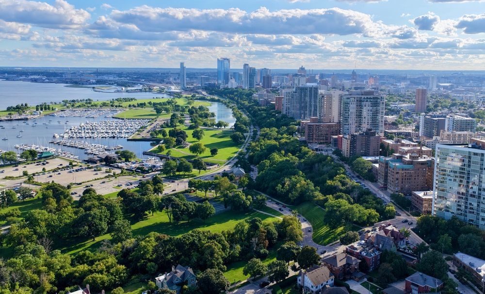 Aerial view of verdant parks on Milwaukee’s lakefront with taller buildings on the right 