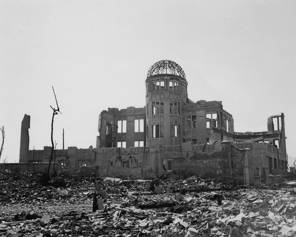Black and white photo of the ruins of a multistory building with a dome on top